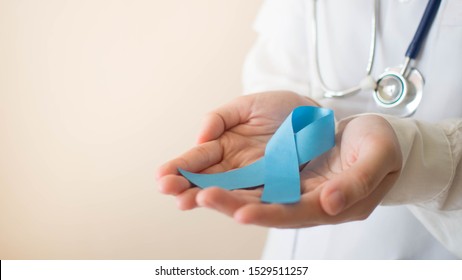 Men's health and Prostate cancer awareness campaign in November month. Close up of doctor hands holding light blue ribbon awareness. Symbol for support men who living w/ cancer. Copy space.
