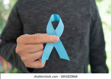 Men's health and Prostate cancer awareness campaign in November month. Close up of young man hands holding light blue ribbon awareness. Symbol for support men who living with cancer.