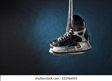 Men's Hockey Skates Hanging On A Dark Background.