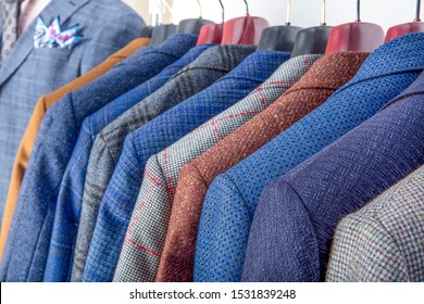 Men's Jackets On Hangers In The Men's Store. Row Of Men's Suit Jackets Hanging In Closet.