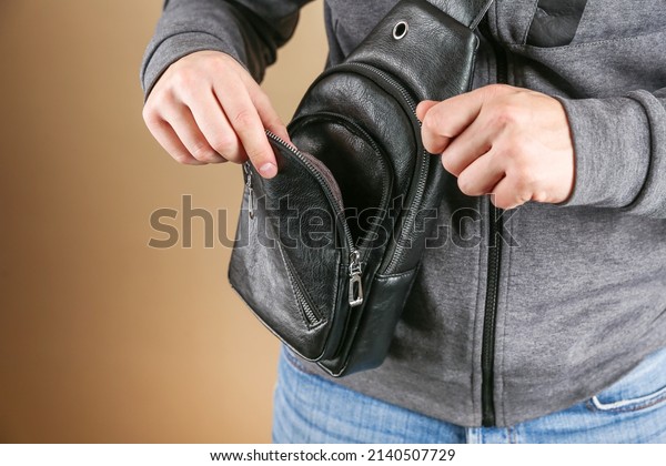 men's leather sling bag is on person close up.
man's hands opens the bag close
up