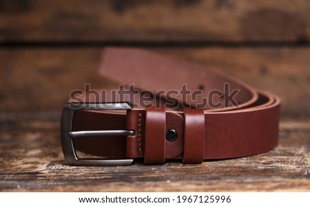 Men's leather trouser red belt in the background of aged wood. Men's fashion accessories closet. Genuine leather, handmade