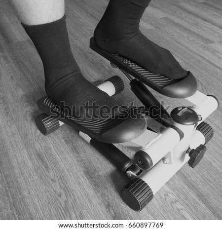 Men's legs in black socks stand on a stepper (side view)