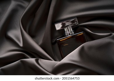 Men's perfume bottle in satin cloth draperies. - Shutterstock ID 2051564753
