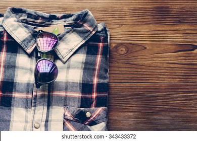 Men's plaid shirt and colored glasses on a wooden background. Top view, copy space. - Powered by Shutterstock