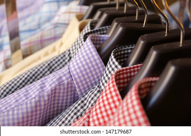 Men's plaid shirts in different colors on hangers in a retail shop - Powered by Shutterstock