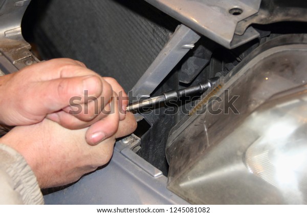 Men\'s rough\
hand unscrews the socket wrench with an extension cord car\
headlight - repair of vehicles,\
disassembling