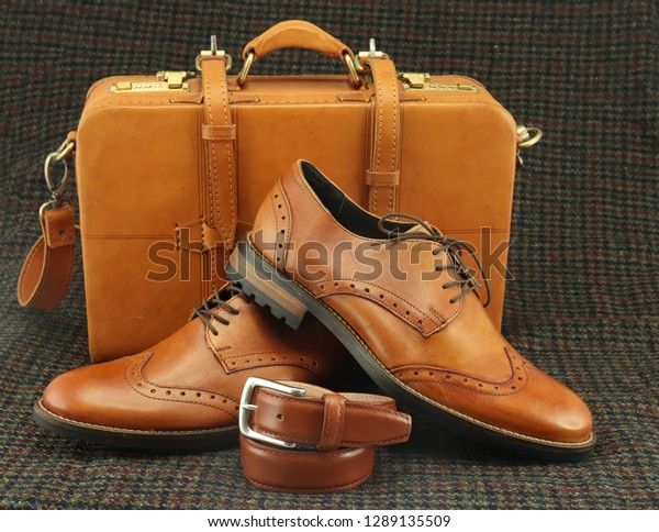 Men\'s shoes, a matching belt and a tan bag. These\
three accessories match perfectly and go well to make a sharp\
looking formal outfit.