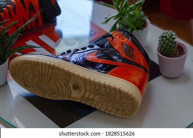 
Men's Sports Basketball Orange-black Sneaker Air Jordan Retro 1 High Shattered Backboard SBB And On A Glass Table And Blurred Background. In Prague On October 5, 2020 In The Czech Republic