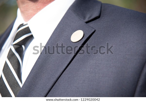Mens suit Lapel pin closeup of tailored business\
suit and tie corporate\
meeting