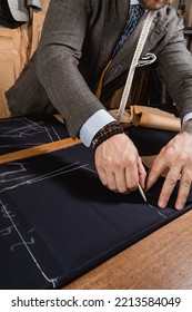 Men's Suit Maker Working On A Design, With Measuring Tape Hanging Around His Neck