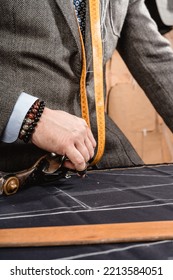 Men's Suit Maker Working On A Design, With Measuring Tape Hanging Around His Neck