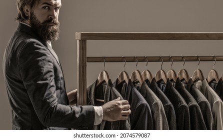 Men's Suit, Tailor In His Workshop. Elegant Man's Suits Hanging In A Row. Luxury Mens Classic Suits On Rack In Elegant Men's Boutique.