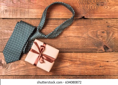 Men's Tie And Gift On A Wooden Background.