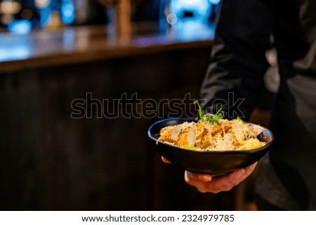 Men's waiter hands hold a Caesar salad with croutons, cheese, eggs, tomatoes and grilled chicken in pub