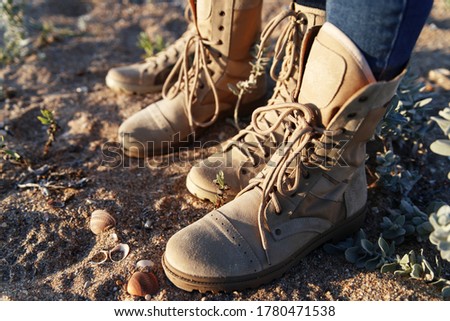 Men's and women's beige lace-up boots for hiking and outdoor activities on sand background. Caucasus, Russia