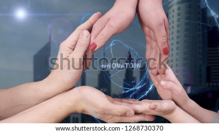 Men's, women's and children's hands show a hologram Innovation. The family holds a magical inscription on the background of a modern city