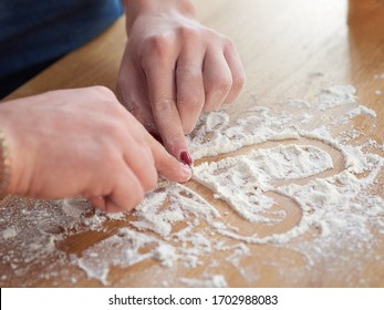 men's and women's hands draw a heart on a table covered with flour. baker's hand closeup.couple together Cooking pizza, bread during coronavirus - Powered by Shutterstock