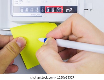 Mens's Hand Writing Down The Consumption Reading Of Natural Gas At Home. Gas Meter. Close-up, Selective Focus.