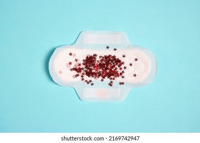 Menstrual Pad With Red Glitter Stars On Blue Background. Menstruation Cycle Period, Woman Hygiene And Comfort Concept.
