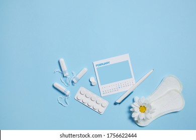 Menstrual Sanitary Tampon, Pad, Pain Pills During Menstruation And White Chamomile Flower On Blue Background, Feminine Calendar With Mock Up. Feminine Hygiene Products. Top View.