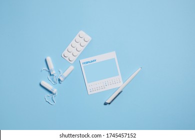 Menstrual Sanitary Tampon, Pain Pills During Menstruation On Blue Background, Feminine Calendar With Mock Up. Feminine Hygiene Products. Top View.