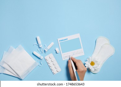 Menstrual Tampon, Pad, Pain Pills And White Chamomile Flower On Blue Background, Feminine Calendar With Copy Space. Care Of Hygiene During Menstruation. Top View. Mock Up