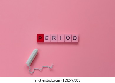 Menstruation Concept: Word Period Spelled With Pink Letters On Pink Background With A Tampon