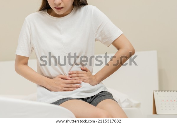 Menstruation, period cycle day of monthly, hurt\
asian young woman, female hand in stomachache, suffer from PMS\
premenstrual, belly or abdomen pain on bed at home. Health problem\
Inflammation in\
body