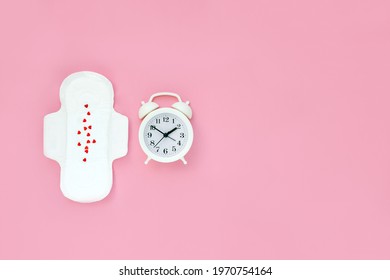 Menstruation Sanitary Soft Pad And White Alarm Clock On Pink Background. Hygiene Protection For Woman In Critical Days. Menstrual Cycle Period. Copy Space