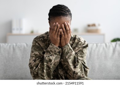 Mental Breakdown. Depressed Black Military Woman Covering Face With Hands, Upset African American Soldier Female In Camouflage Uniform Sitting On Couch And Crying, Suffering PTSD, Copy Space