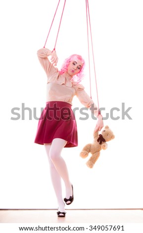 Mental disorder concept. Young woman girl stylized like marionette puppet on string with teddy bear toy isolated on white background