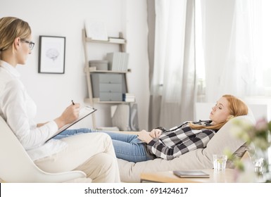 Mental Health Concept - Patient Lying On A Couch In Psychologist Office, Psychologist Taking Notes