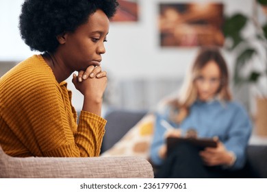 Mental health, depression and psychology with a black woman in therapy, talking to a professional. Anxiety, stress or support with a young patient in session with a psychologist for grief counseling - Powered by Shutterstock