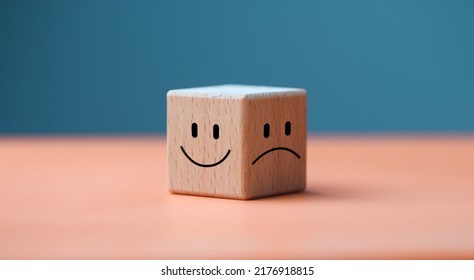 Mental health and emotional state concept, Smile face in bright side and sad face in dark side on wooden block cube for positive mindset selection. - Shutterstock ID 2176918815