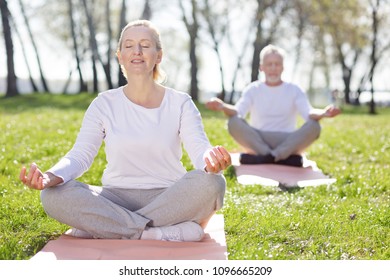 Mental health. Pleasant aged woman feeling peaceful while practicing yoga - Shutterstock ID 1096665209