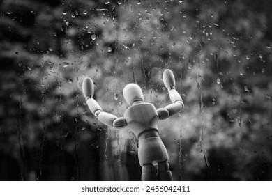 Mental health problem concept. Wooden mannequin by the window in the rain. Sadness, loneliness, Blue Monday, depression or seasonal affective disorder - Powered by Shutterstock