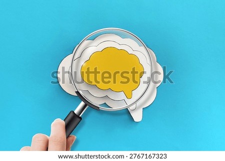Mental health and problems with memory. A hand holding a magnifying glass is examining the human brain.