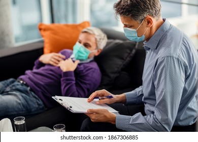 Mental Health Professional Analyzing Reports Oh His Patient While Having Therapy Session With Him During COVID-19 Pandemic.