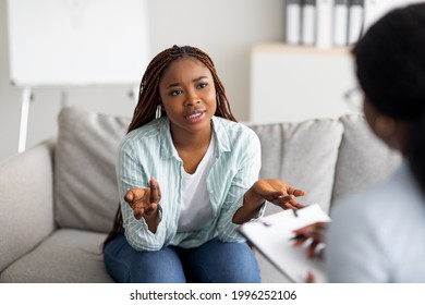 Mental health and psychological assistance concept. Young worried black woman having counseling session with psychotherapist at clinic. PTSD disorder, anxiety treatment