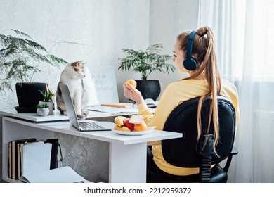 Mental Health And Work. Work Life Balance. Young Woman In Headphones Near Laptop At Home Office Resting After Work. Freelancer Woman Play With Cat And Eating Health Food, Taking Break Time