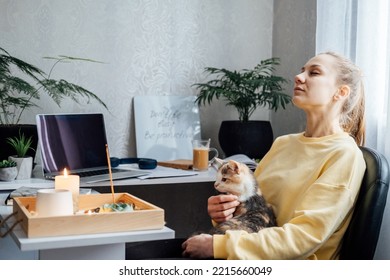 Mental health and work. Work life balance. Young woman with cat lighting candles, relaxing and resting after work at home office. freelancer woman play with cat. Taking break time - Powered by Shutterstock