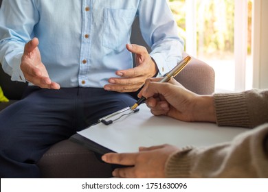 Mental illness. Female psychologists is writing male patient information to a clipboard. The patient has head sickness and confusion while discussing psychotic symptoms with a doctor or psychiatrist.  - Powered by Shutterstock