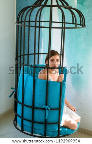mental mind. prisoner woman in cage - home confinement. freedom of cute girl in cage chair. fashion slave in captivity of beauty. modern furniture design and home comfort. pretty woman in iron cage.