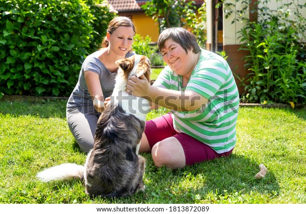 mentally disabled\
woman with a second woman and a companion dog, concept learning by\
animal assisted living