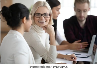 Mentor Explaining Project Task To Intern. Female Professionals Talking At Workplace. New Employee Consulting Friendly Colleague. Workers Discussing Office News. Cooperation, Mentorship Concept