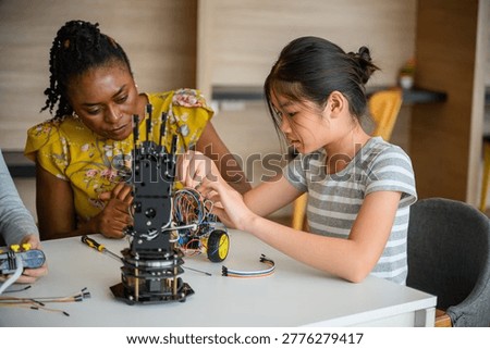 Mentor instructing student assembling robotic hand and wiring electronics in STEM class