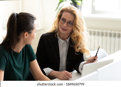Mentoring on workplace. Friendly capable mature businesswoman worker employee teaching training younger woman colleague intern trainee, explaining task, proposing new idea, helping in work at project