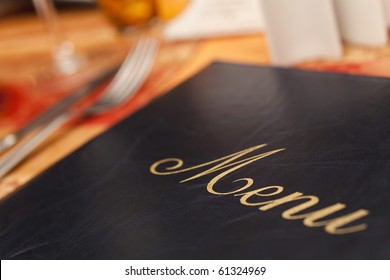 A Menu And Knife And Fork Cutlery Laid On A Restaurant Table