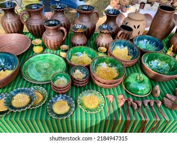 Merchandise on annual biggest crafts market in Latvian Ethnographic Open Air museum. Bright green traditional glazed ceramic cups and bowls, brown vases. Riga, Latvia - June 4, 2022